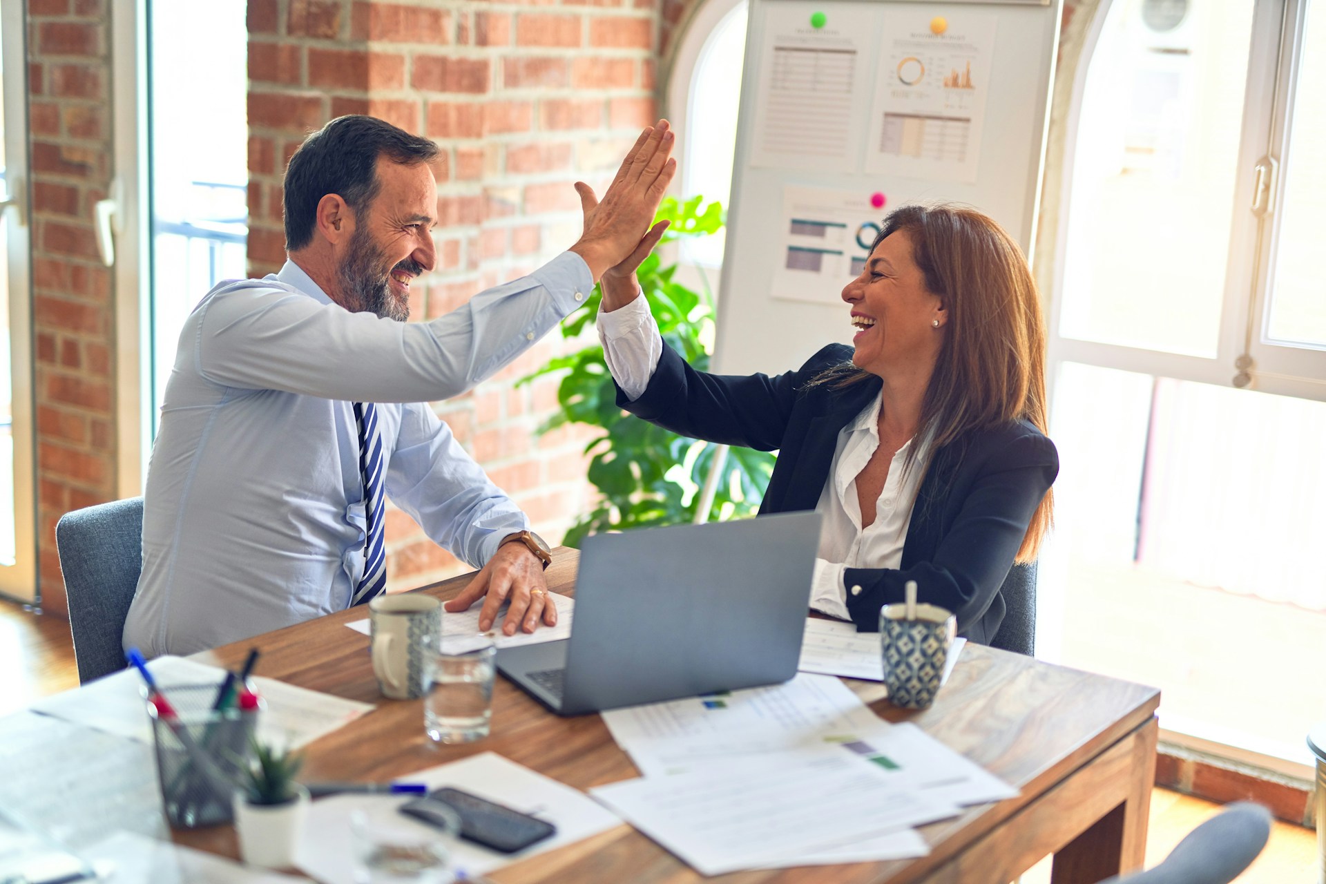 Twee collega's vieren een succesvolle referral met een high-five